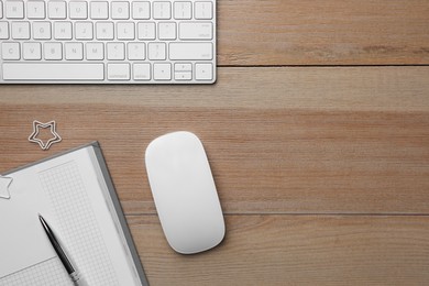 Wireless mouse, notebook, pen and computer keyboard on wooden table, flat lay. Space for text