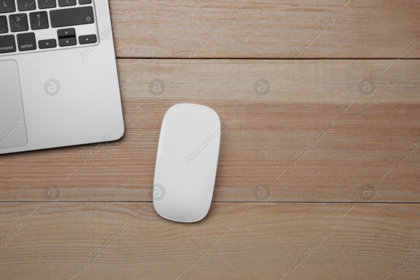 Photo of Wireless mouse and laptop on wooden table, top view. Space for text