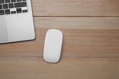 Wireless mouse and laptop on wooden table, top view. Space for text