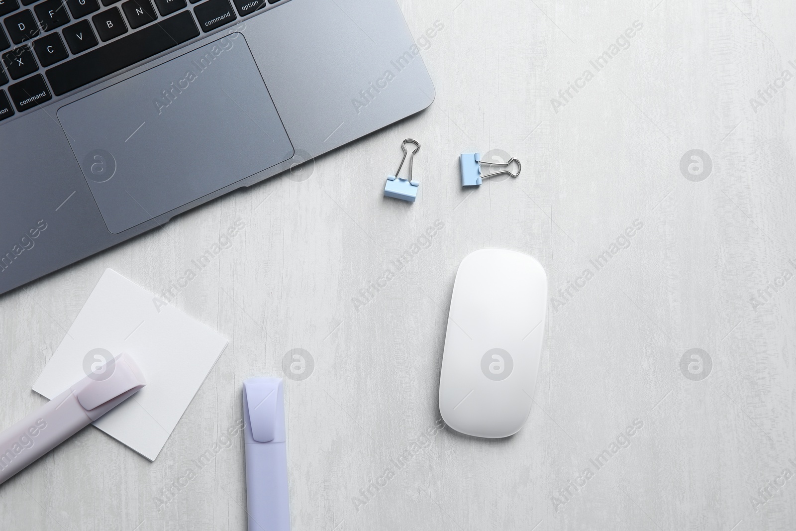 Photo of Wireless mouse, stationery and laptop on light wooden table, flat lay