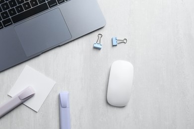 Photo of Wireless mouse, stationery and laptop on light wooden table, flat lay