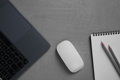 Photo of Wireless mouse, notebook, pencils and laptop on grey textured table, flat lay