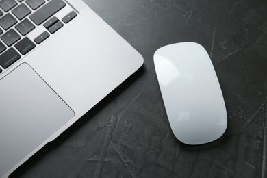 Photo of Wireless mouse and laptop on dark textured table, top view