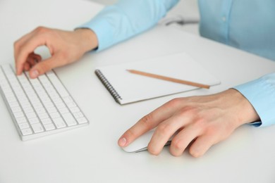 Photo of Man working with wireless mouse and computer keyboard at white table indoors, closeup