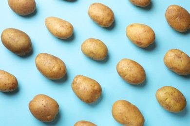 Photo of Many fresh potatoes on light blue background, flat lay