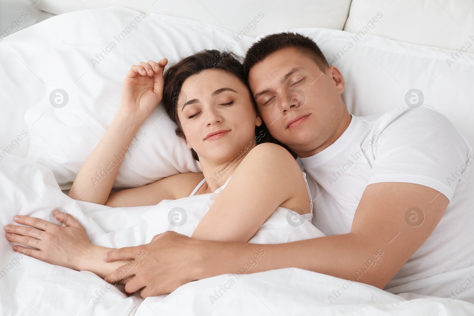 Photo of Lovely couple sleeping together in bed at home, top view