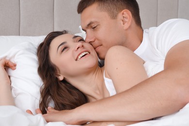 Photo of Lovely couple kissing in bed at home