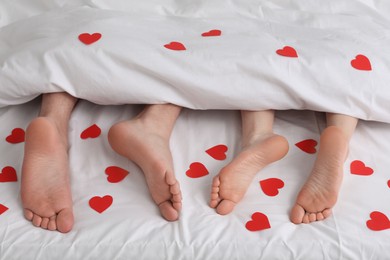 Photo of Couple lying in bed with red hearts, closeup