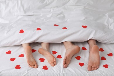 Photo of Couple lying in bed with red hearts, closeup
