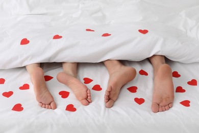 Photo of Couple lying in bed with red hearts, closeup