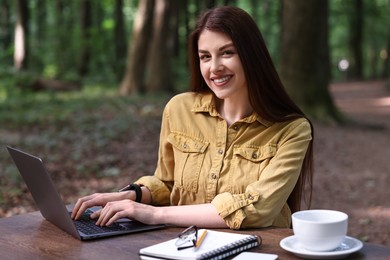 Smiling freelancer working with laptop at table outdoors. Remote job