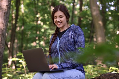 Photo of Smiling freelancer working with laptop in forest. Remote job