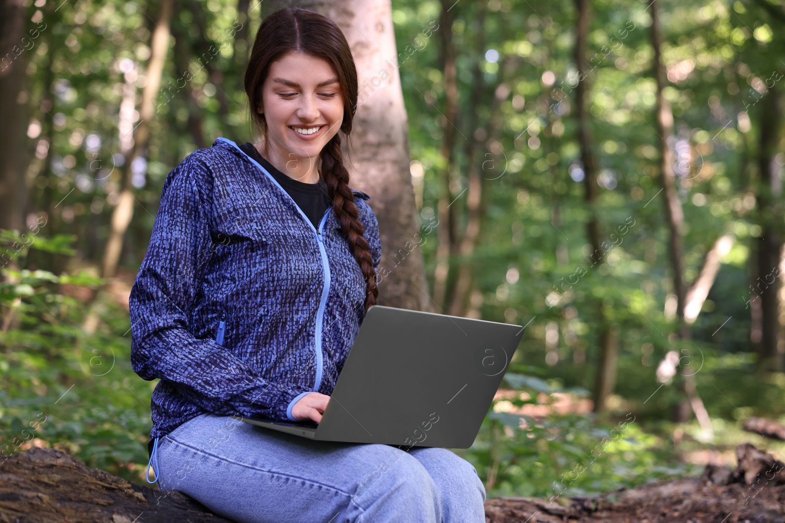 Photo of Smiling freelancer working with laptop in forest, space for text. Remote job