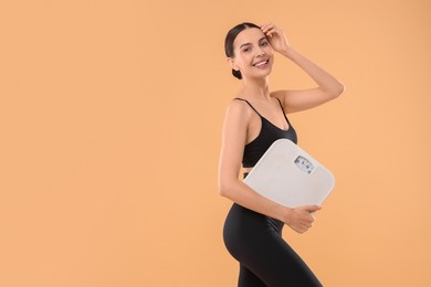 Photo of Diet and weight loss concept. Happy young woman with floor scale on beige background. Space for text