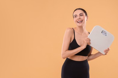 Photo of Diet and weight loss concept. Happy young woman with floor scale on beige background. Space for text