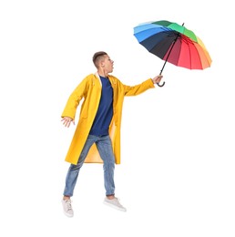 Photo of Young man with rainbow umbrella jumping on white background