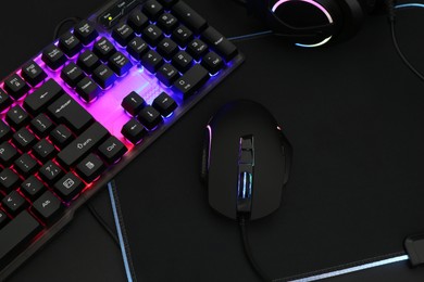 Photo of Computer mouse, headset and RGB keyboard on dark background, above view