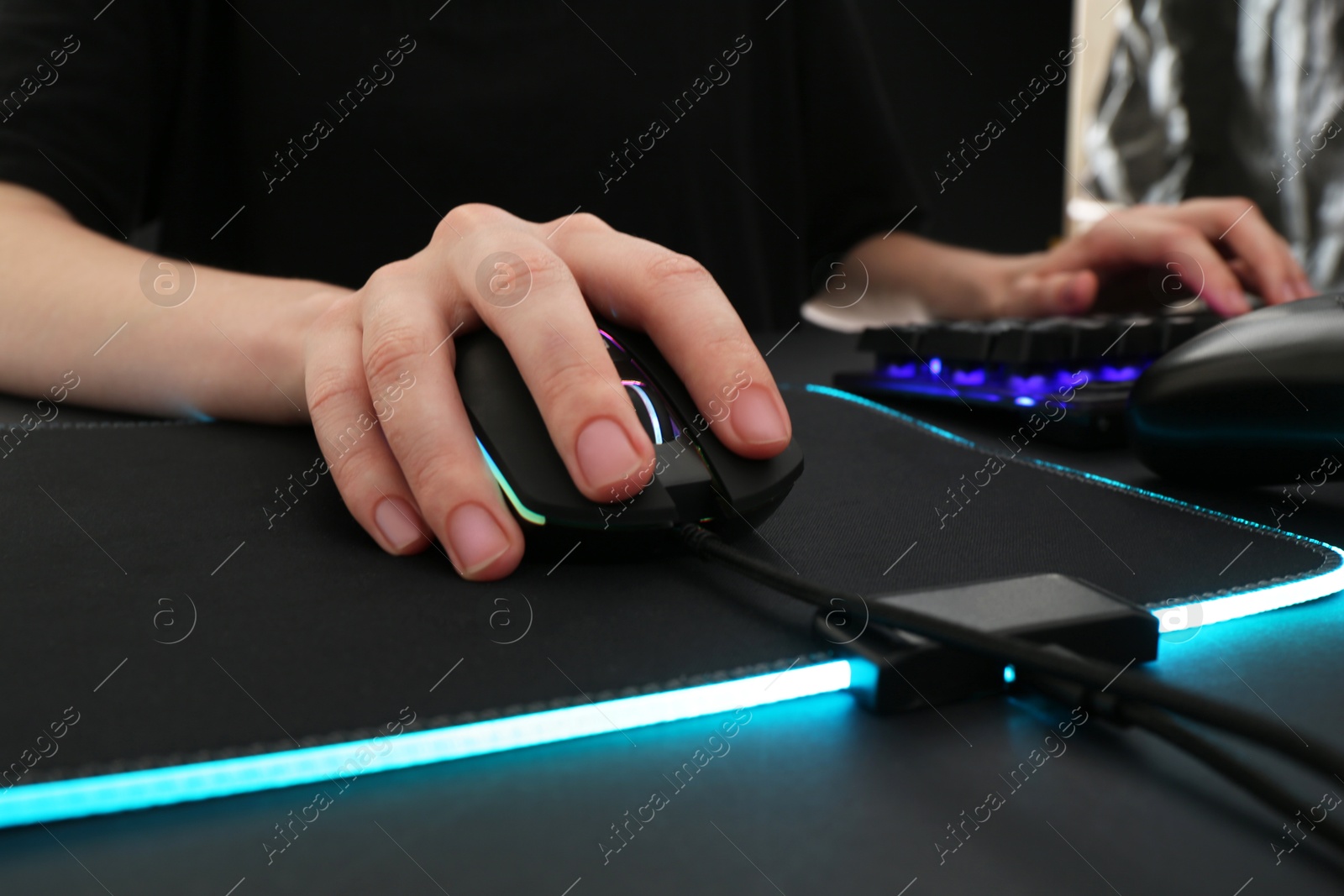 Photo of Gamer using modern wired computer mouse at dark table, closeup