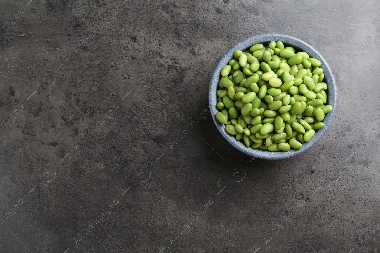 Photo of Raw green edamame soybeans on grey table, top view. Space for text