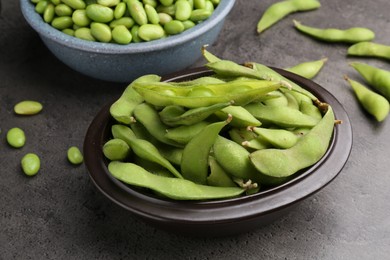 Photo of Raw green edamame soybeans and pods on grey table, closeup