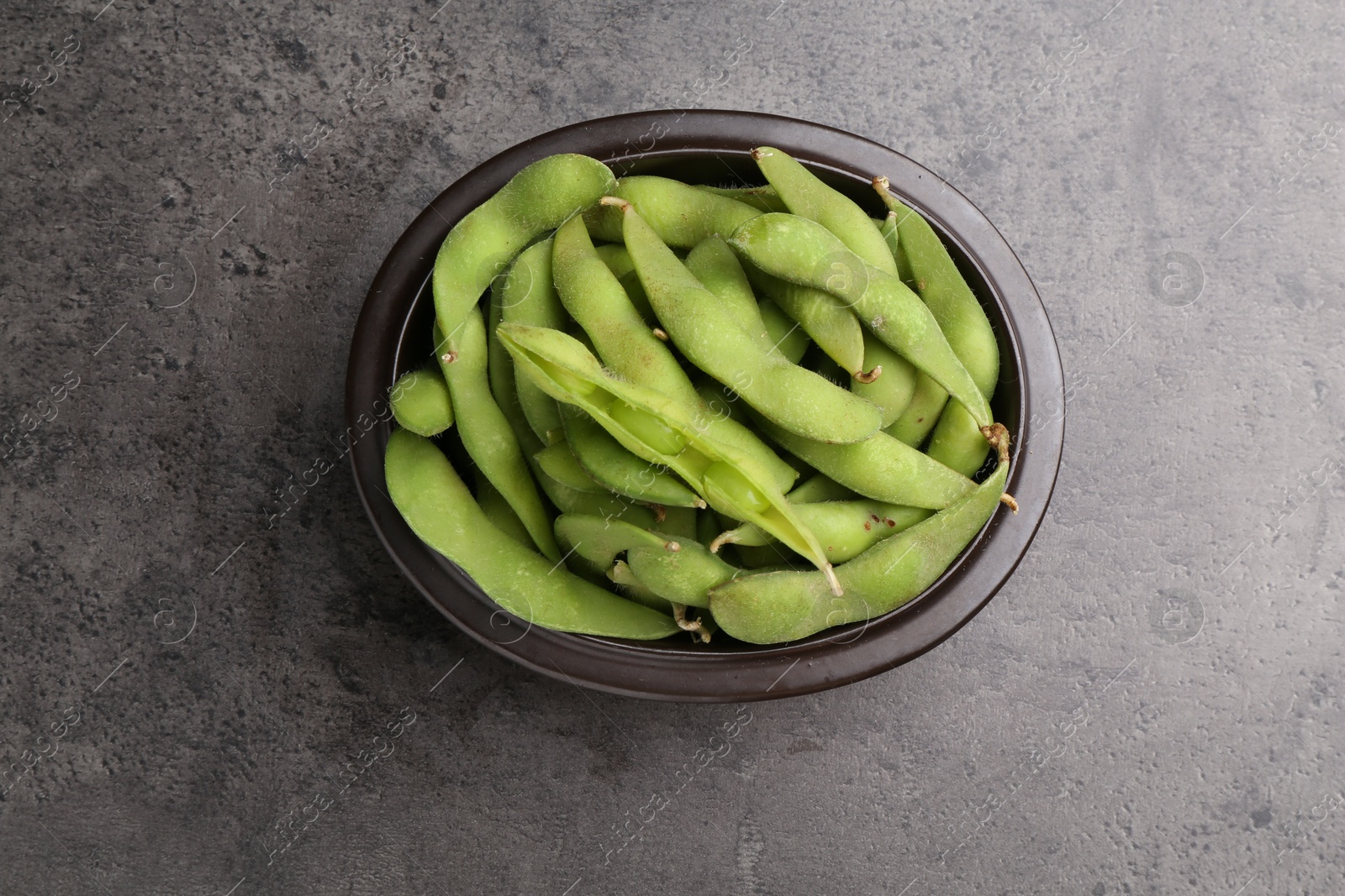 Photo of Raw green edamame pods on grey table, top view