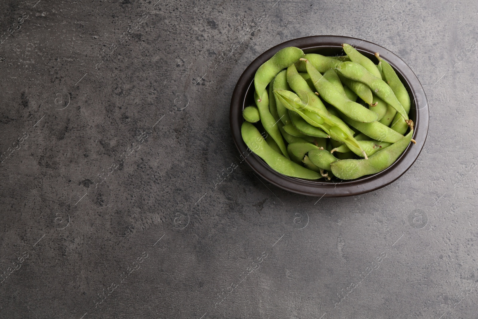 Photo of Raw green edamame pods on grey table, top view. Space for text