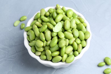 Photo of Fresh edamame soybeans in bowl on grey textured table, above view