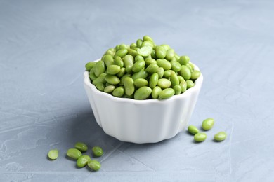 Photo of Fresh edamame soybeans in bowl on grey textured table, closeup