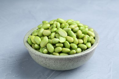 Photo of Fresh edamame soybeans in bowl on grey textured table, closeup