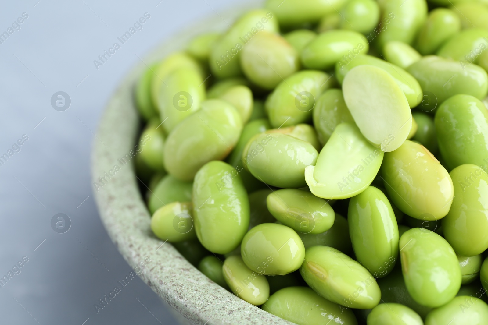 Photo of Fresh edamame soybeans in bowl on grey table, closeup