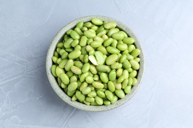 Photo of Fresh edamame soybeans in bowl on grey textured table, top view