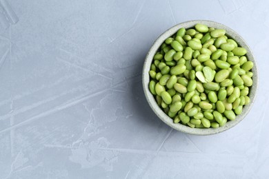 Photo of Fresh edamame soybeans in bowl on grey textured table, top view. Space for text