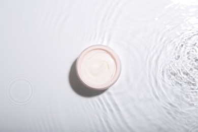 Cosmetic product. Jar with cream in water on light background, top view