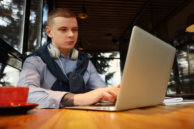 Photo of Young male student with laptop studying at table in cafe