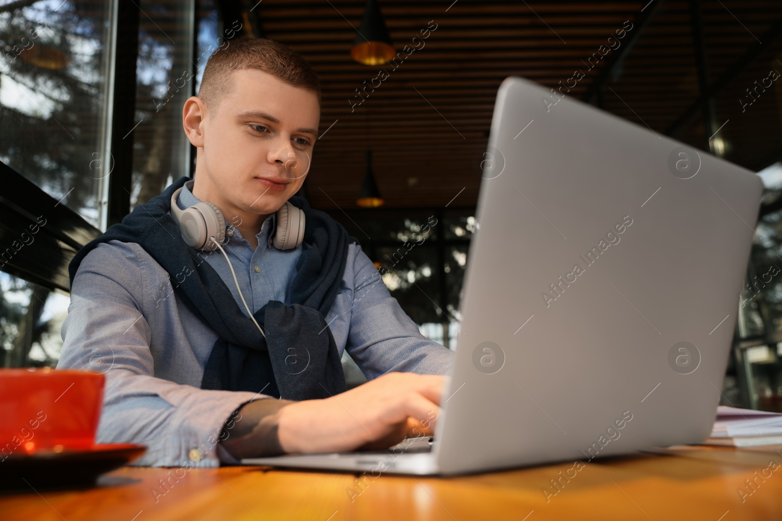 Photo of Young male student with laptop studying at table in cafe