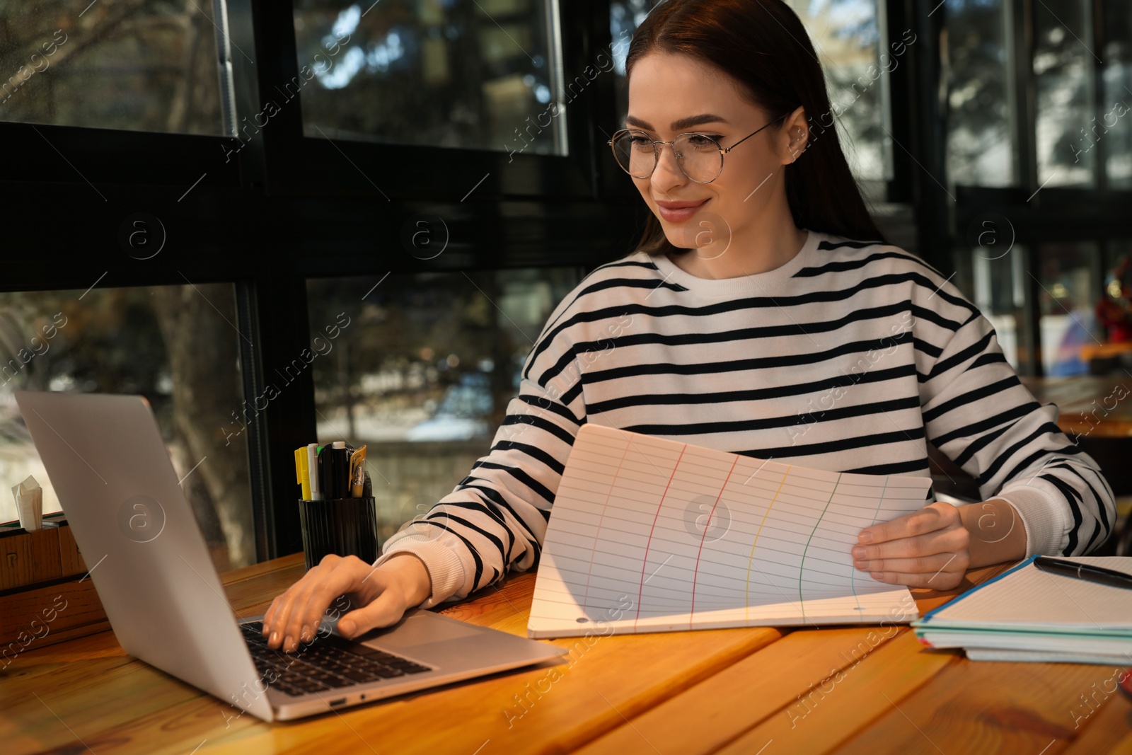 Photo of Young female student with laptop studying at table in cafe