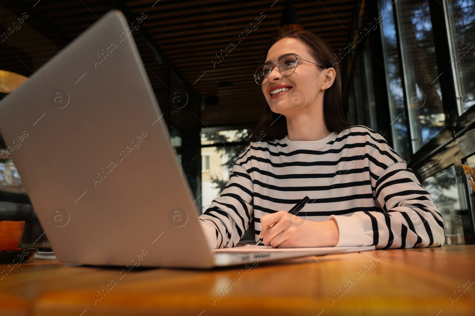 Photo of Young female student with laptop studying at table in cafe