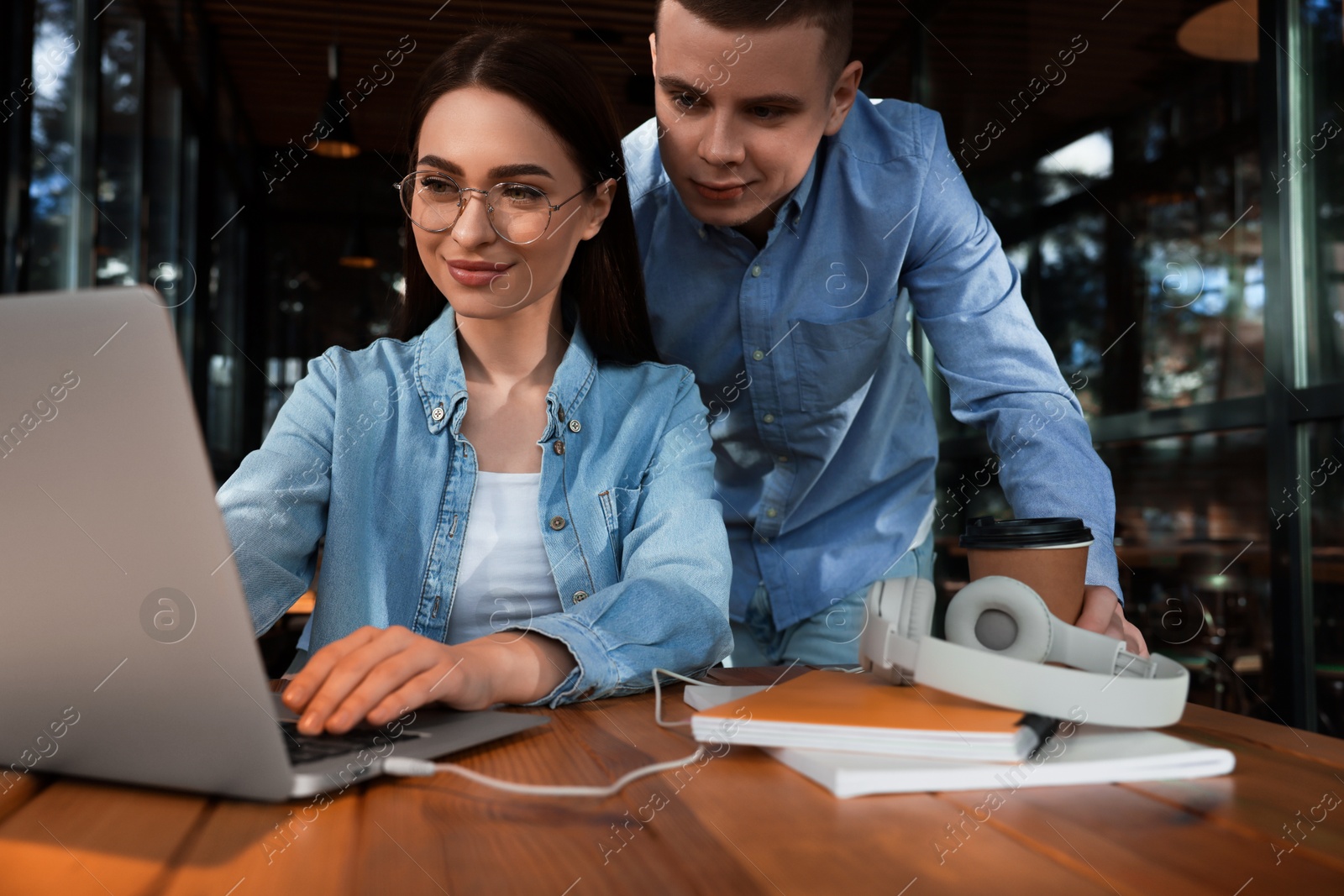 Photo of Young students with laptop studying at table in cafe