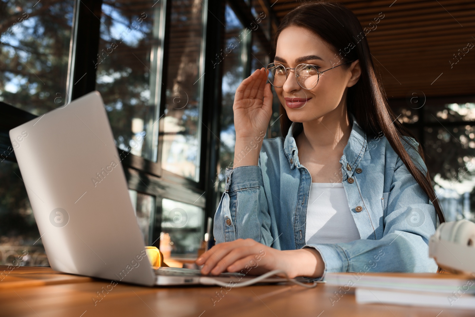 Photo of Young female student with laptop studying at table in cafe