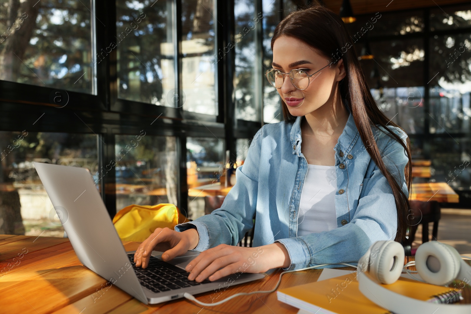 Photo of Young female student with laptop studying at table in cafe