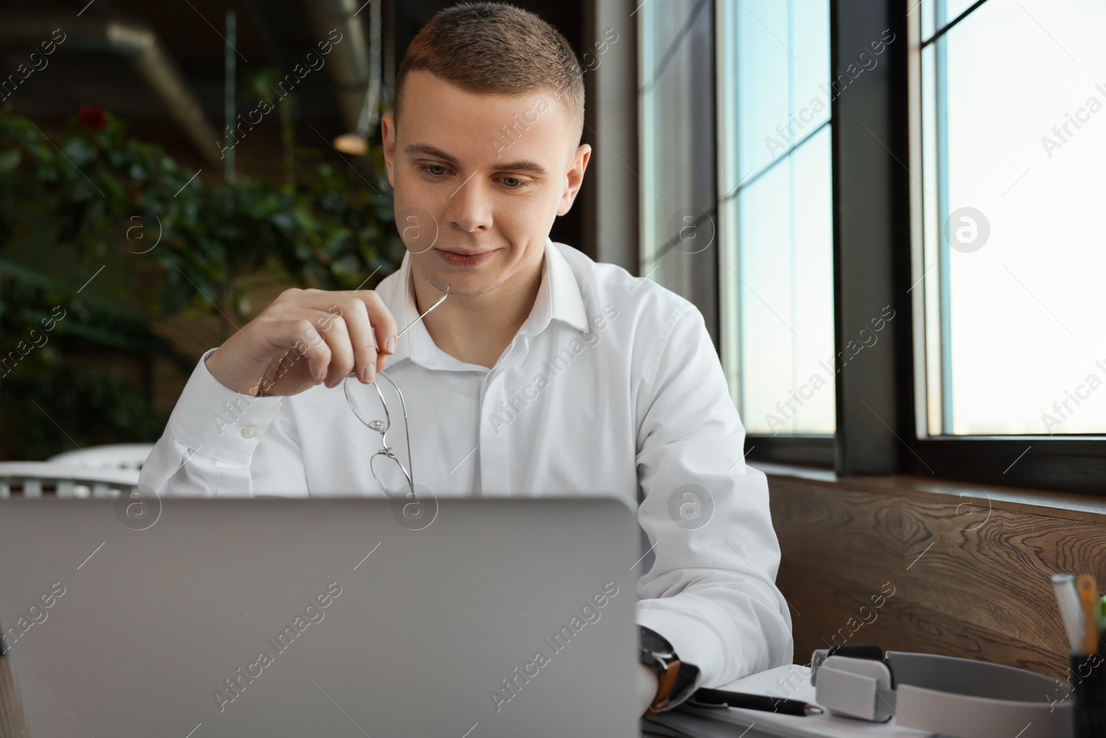 Photo of Young male student with laptop studying at table in cafe