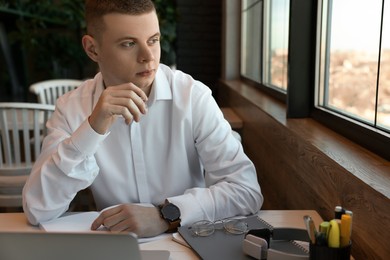 Photo of Young male student with laptop studying at table in cafe