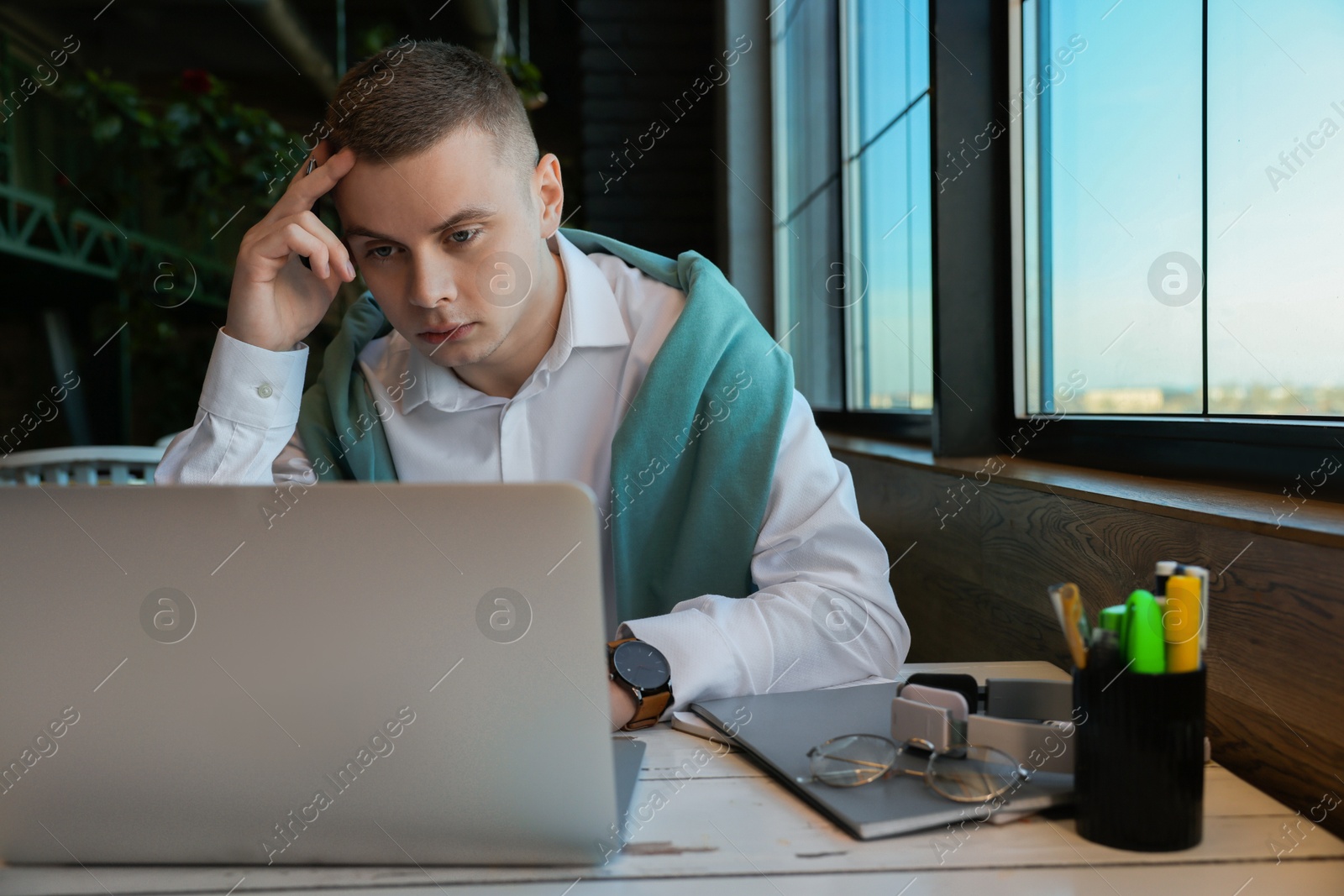 Photo of Young male student with laptop studying at table in cafe