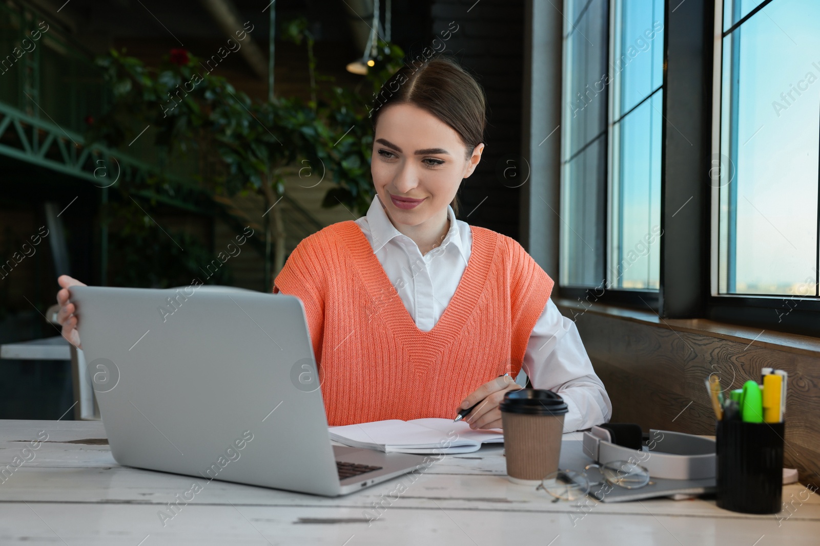 Photo of Young female student with laptop studying at table in cafe