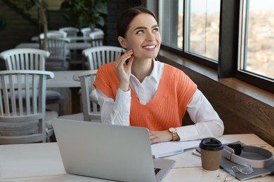 Photo of Young female student with laptop studying at table in cafe