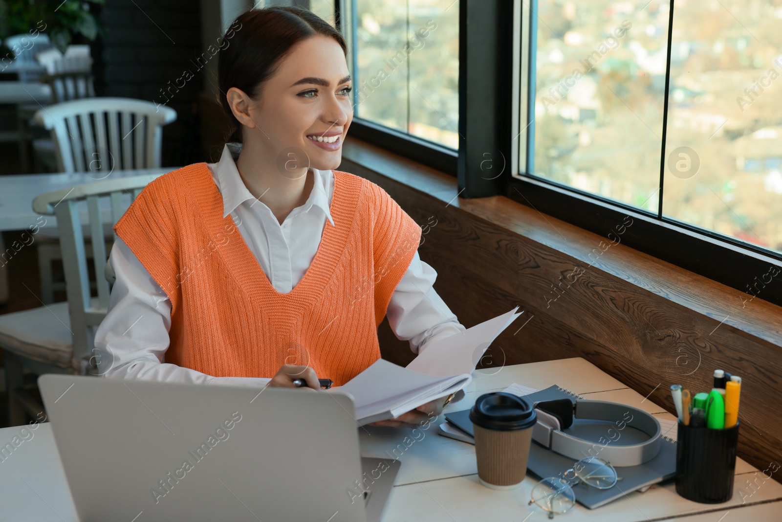 Photo of Young female student with laptop studying at table in cafe