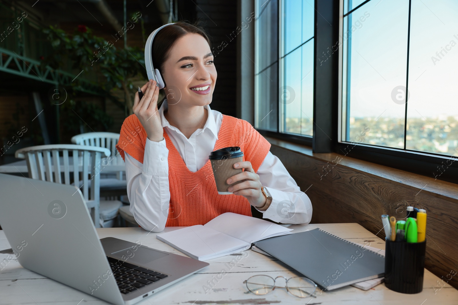 Photo of Young female student with laptop and coffee studying at table in cafe