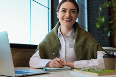 Photo of Young female student with laptop studying at table in cafe