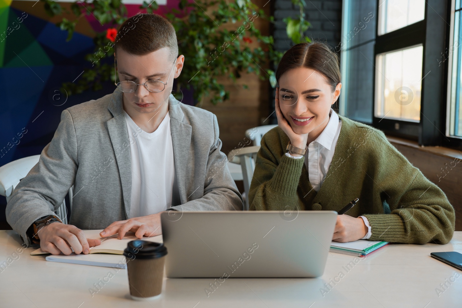 Photo of Young students with laptop studying at table in cafe