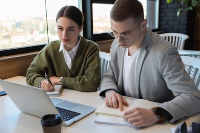 Photo of Young students with laptop studying at table in cafe